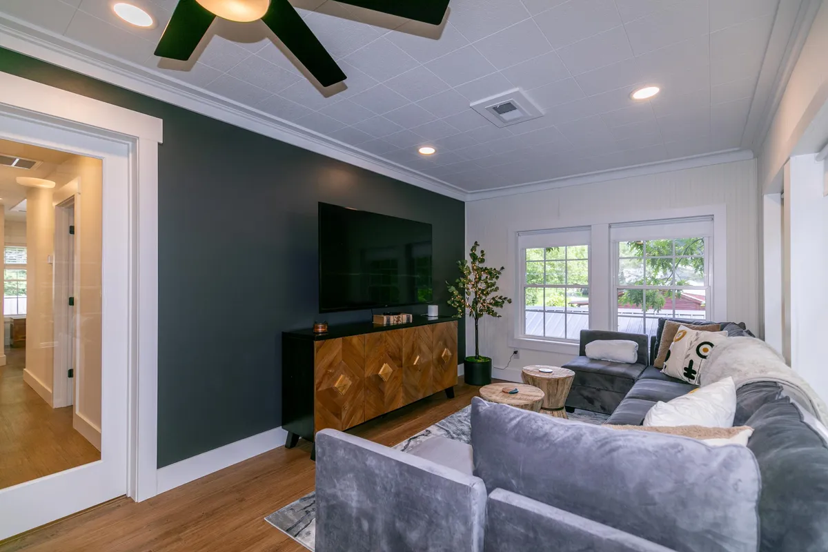 A cozy seating area with a plush sofa, decorative plant, coffee table, and a wall-mounted TV. The relaxed setup invites lounging, movie nights, and casual gatherings—all in a homey setting.