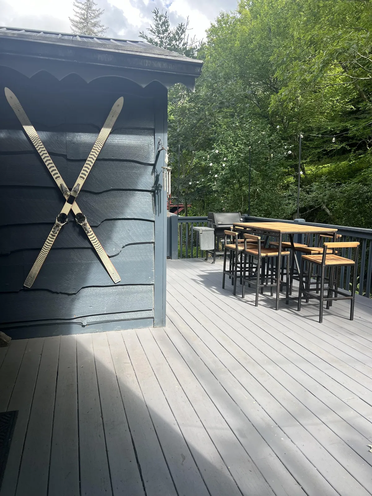 Outdoor bar seating area with wooden skis mounted on the wall, offering a casual spot for drinks, meals, or relaxed conversations. This deck space enjoys sunset views and encourages lively group barbecues or post-adventure gatherings.